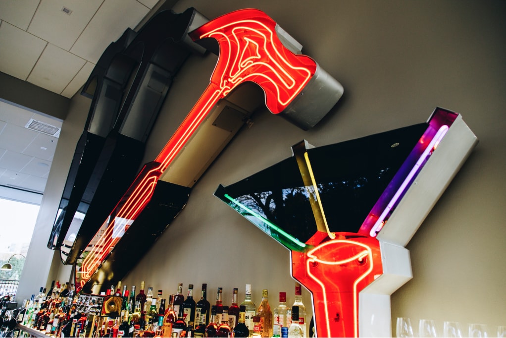 The giant neon Hammer Hammer Nail sign mounted behind the bar